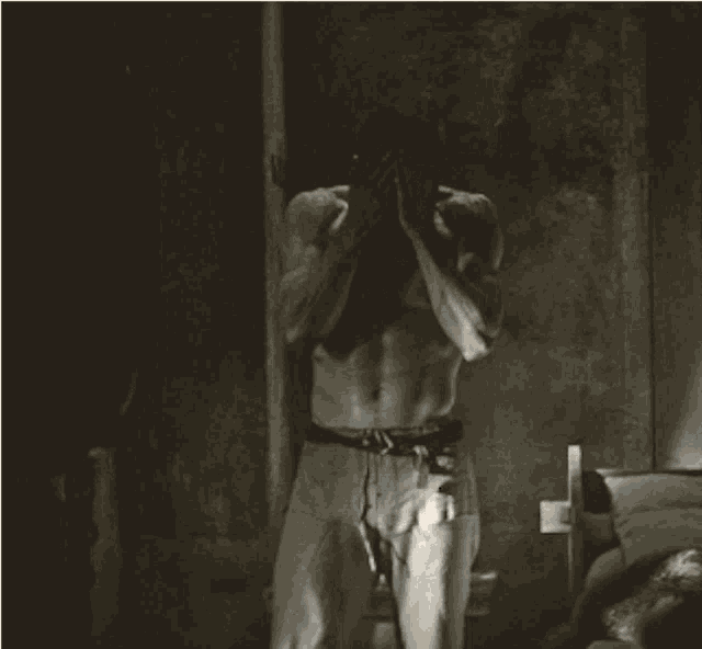 a man without a shirt is standing in a dark room with his mouth open
