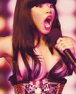 a woman with pink hair is singing into a microphone