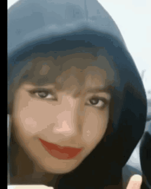 a close up of a woman 's face wearing a hoodie and red lipstick .