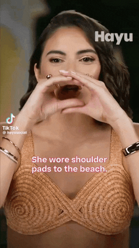 a woman making a heart with her hands and the words she wore shoulder pads to the beach on the bottom