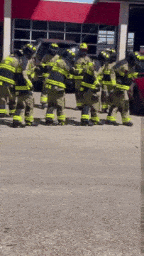 a group of firefighters are standing outside of a fire station