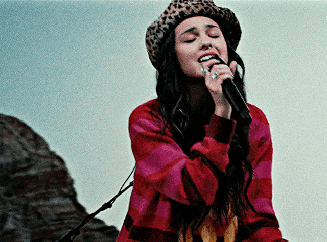 a woman singing into a microphone wearing a leopard hat