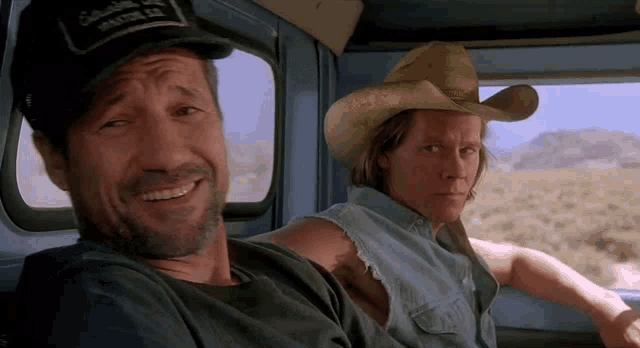 two men in cowboy hats are sitting in a blue truck