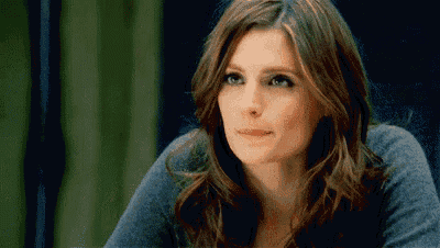 a close up of a woman 's face with a serious look on her face while wearing a blue sweater .