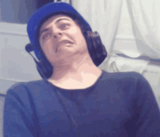 a man wearing headphones and a blue hat makes a face