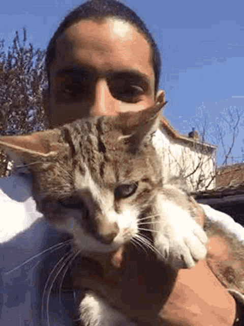 a man is holding a cat in front of his face .