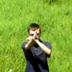 a boy in a blue shirt is standing in a field with his hands crossed