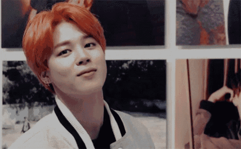 a young man with red hair is standing in front of a collage of pictures