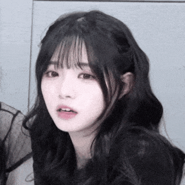 a girl with long black hair and bangs looks at the camera with her mouth open