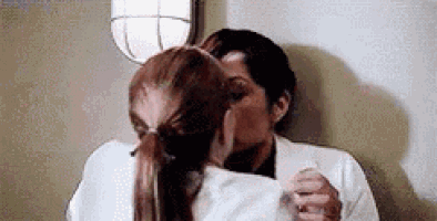 a man and a woman are kissing each other in a room .