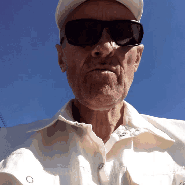 an older man wearing sunglasses and a white shirt