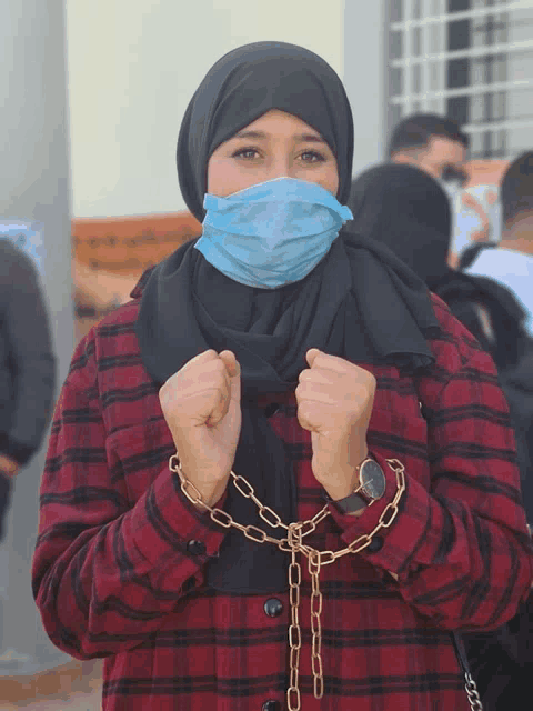 a woman wearing a face mask is chained to a chain around her neck