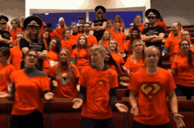 a group of people wearing orange shirts with a superman logo on the front