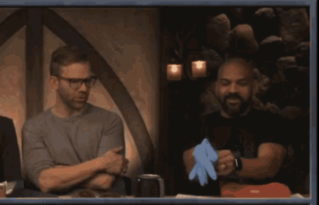 a man is putting a blue glove on another man