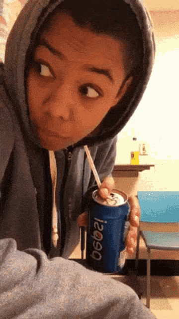 a person in a hoodie drinking from a can of pepsi