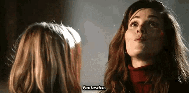 two women are standing next to each other and talking to each other .