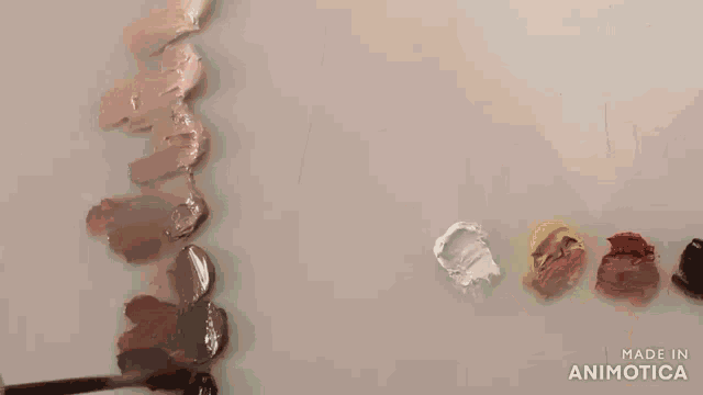 a person is painting a woman 's face with a brush and the words made in animotica are on the bottom