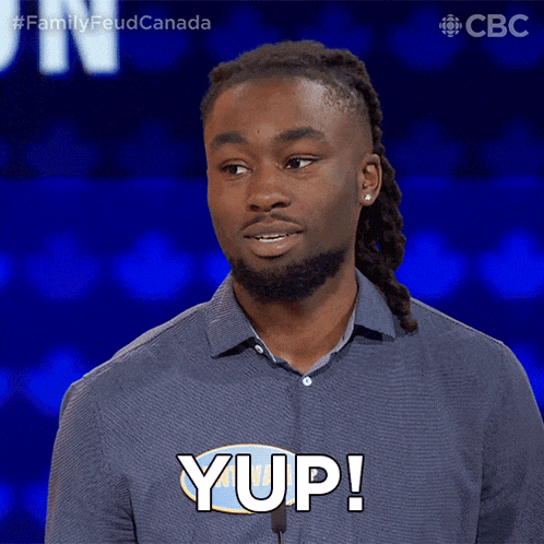 a man in a blue shirt says yup in front of a microphone