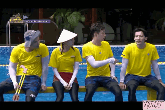 a group of people in yellow shirts are sitting next to a pool with a purple sign above them that says run