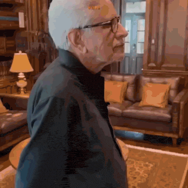 a man wearing glasses and a black shirt stands in a living room