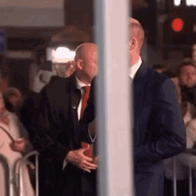 a man in a suit and tie is talking to another man