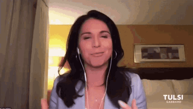 a woman wearing headphones is smiling in front of a screen that says tulsi gabbard on it