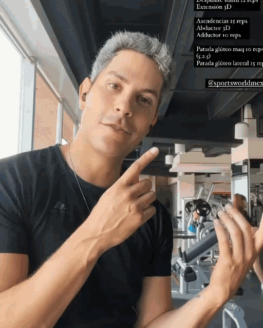 a man in a black shirt is pointing at something in the gym