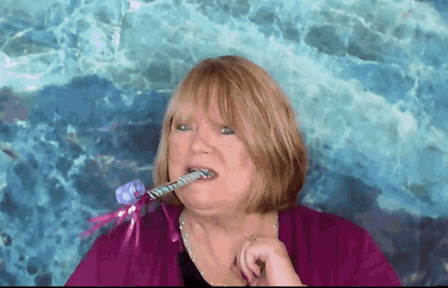 a woman in a purple shirt is holding a unicorn wand in her mouth