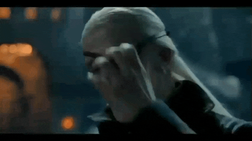 a man is holding another man 's head in a dark room .