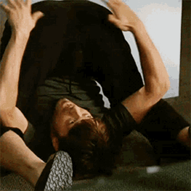 a man in a black shirt is laying on his back with his legs crossed