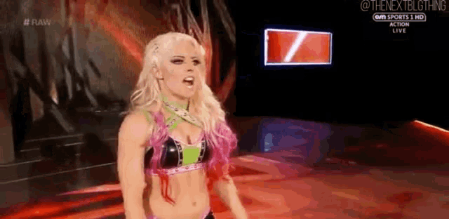 a woman in a wrestling outfit is standing on a stage in front of a screen .