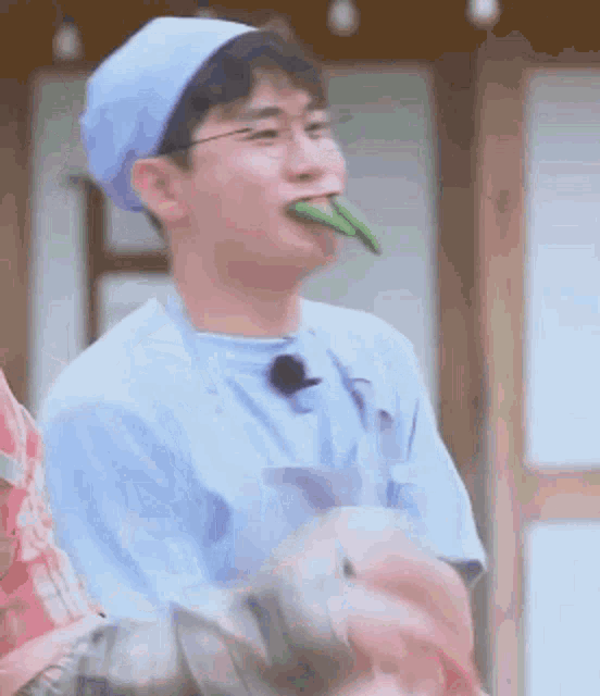 a young man in a chef 's hat is eating a green vegetable .