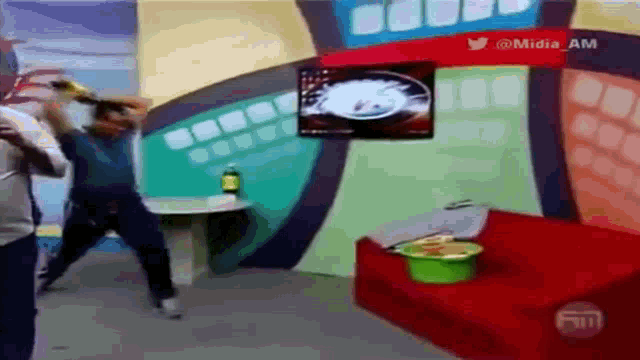a man is dancing in front of a red couch and a sign that says @midia am