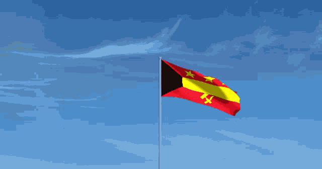 a red yellow and black flag is flying in a blue sky