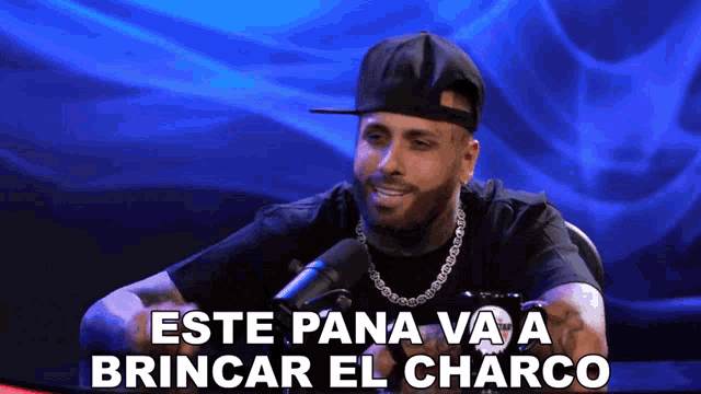 a man wearing a baseball cap and a necklace says " este pana va a brincar el charco "