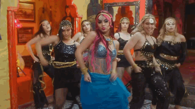 a woman in a blue dress is surrounded by other women in black outfits