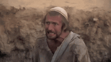 a man wearing a white hat and a dirty shirt is standing in front of a wall .