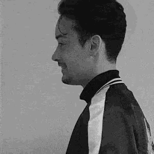 a black and white photo of a young man wearing a black and white jacket .