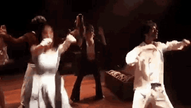a group of people are dancing on a stage with their arms outstretched .