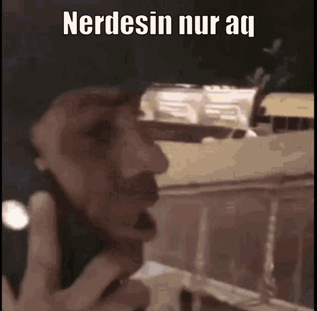 a man is talking on a cell phone in front of a building with a caption that says nerdesin nur aq .