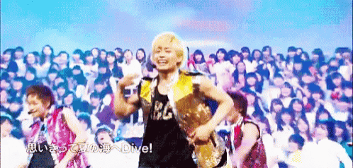 a man in a yellow vest is dancing in front of a crowd with the words " dive " on the screen