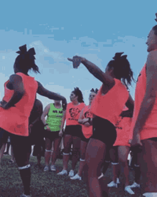 a group of cheerleaders are standing in a circle and one of them is pointing at something