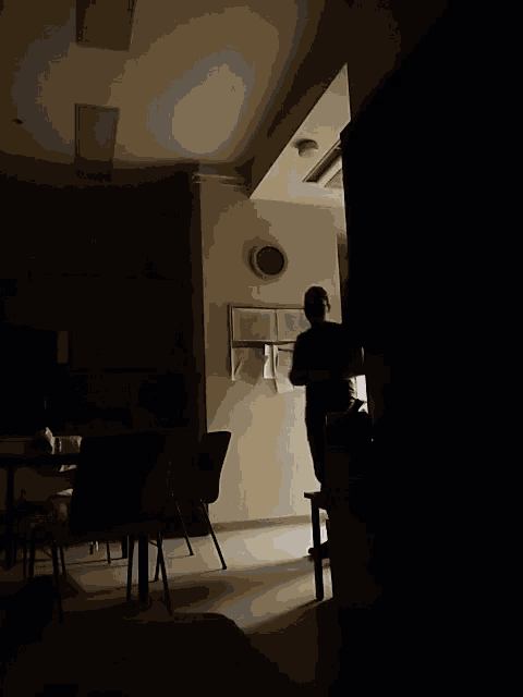 a man in a dark room with a clock on the wall