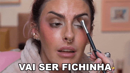 a woman applying makeup with the words vai ser fichinha written above her