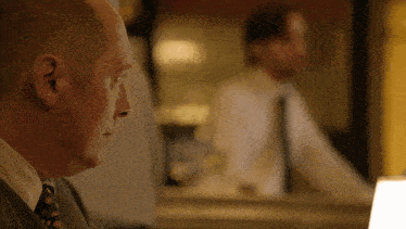 a man in a suit and tie looks at himself in a mirror