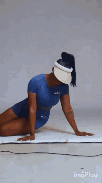 a woman wearing a blue shirt and a hat is kneeling down