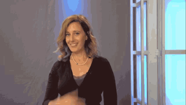 a woman wearing a black sweater and a pearl necklace