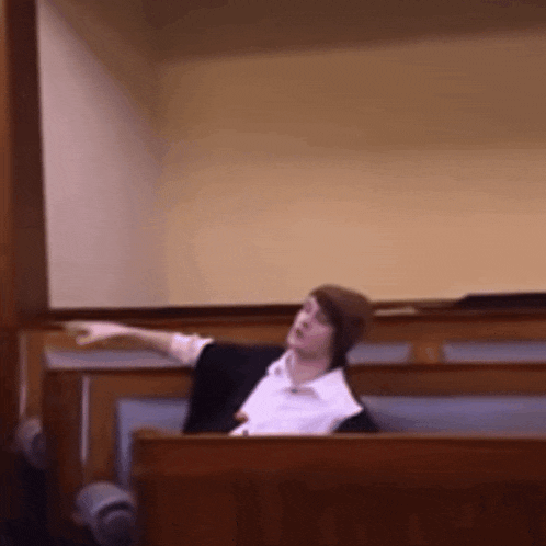 a man sitting in a courtroom giving a speech with his arm outstretched