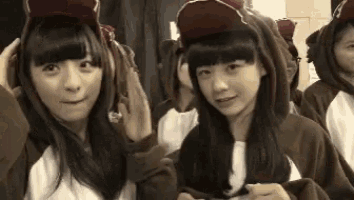 a group of young girls are wearing hoodies and hats .