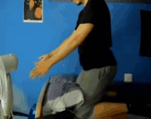 a man in a black shirt is kneeling down in front of a blue wall with a picture on it
